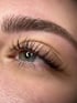 Nahaufnahme eines Auges mit langen, dunklen Wimpern und einer vollen Augenbraue.