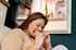 Woman with long brown hair eating a hamburger on the floor in front of an open fridge, representing insulin resistance issues