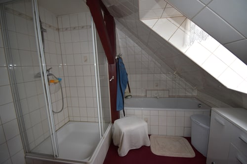 Badezimmer im Dachgeschoss mit Duschkabine, Badewanne unter schräger Decke und Waschmaschine.