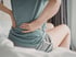 Woman sitting in bed with lower back pain — sciatica and back pain care at Accelerated Medical in Elko, NV