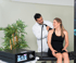 A woman in a black dress undergoes Gainswave therapy on her shoulder as a male doctor operates the device.