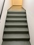 Eine graue Betontreppe führt zu einem hell erleuchteten Flur.