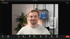 Ein lächelnder Mann in einem weißen Pullover blickt in die Kamera während eines Zoom-Meetings.