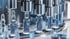 Gläserne Ampullen mit blauer Flüssigkeit in einer automatisierten pharmazeutischen Abfüllanlage aus Edelstahl.
