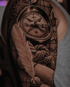 Detailliertes Tattoo auf einem Oberarm mit Kompass, Weltkarte, Seilknoten und einer Schreibfeder in einem Tintenfass.
