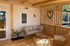 Holzveranda mit Rattan-Sofa, zwei Stühlen, Couchtisch und Herzdekoration an der Wand.