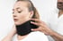 A doctor adjusts a black neck brace on a woman's neck for whiplash treatment.