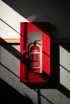 Ein roter Feuerlöscher der Marke Aumüller in einem roten Wandkasten mit Glasscheibe bei dramatischem Lichteinfall.