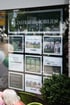 Schaufenster mit "ZASTRAU IMMOBILIEN" Schild und neun Plakaten zu Immobilienangeboten und Dienstleistungen.