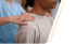 Masseuse in blue scrubs massages a patient's shoulders
