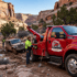 Towing Sandy winch out and recovery service extracting a stuck off-road vehicle from muddy terrain in a rocky canyon environment.