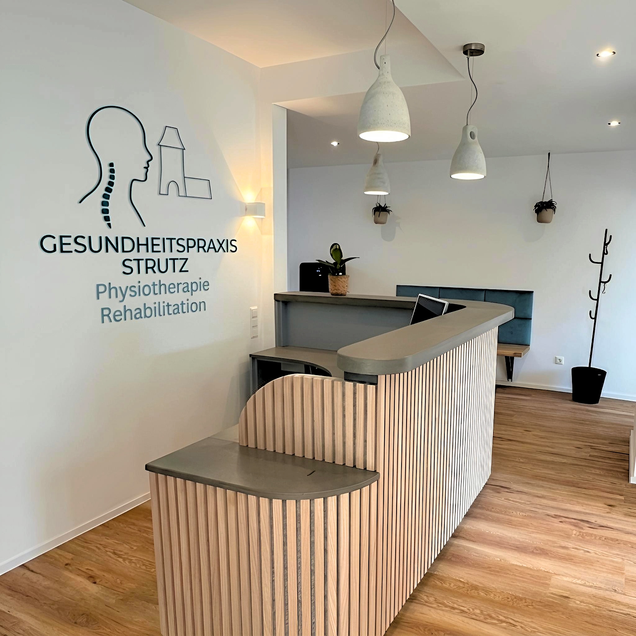 Empfangstresen aus Holz und Beton mit dem Logo der Gesundheitspraxis Strutz
