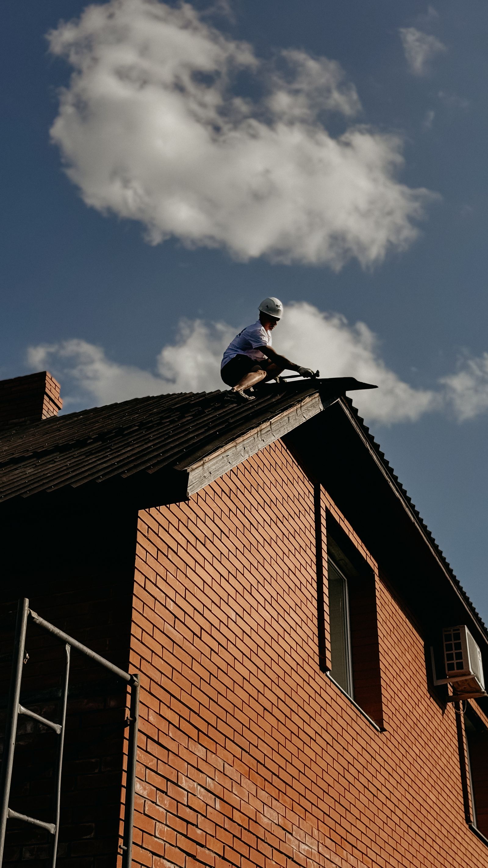 Roofing contractor in protective gear working on a house roof