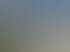 Blick über die Dächer von Bergün mit historischem Kirchturm im Vordergrund, grünen Wiesen und dicht bewaldeten Berghängen sowie felsigen Gipfeln im Hintergrund bei sonnigem Sommerwetter.