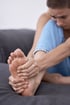 Person massages foot, easing discomfort from peripheral neuropathy.