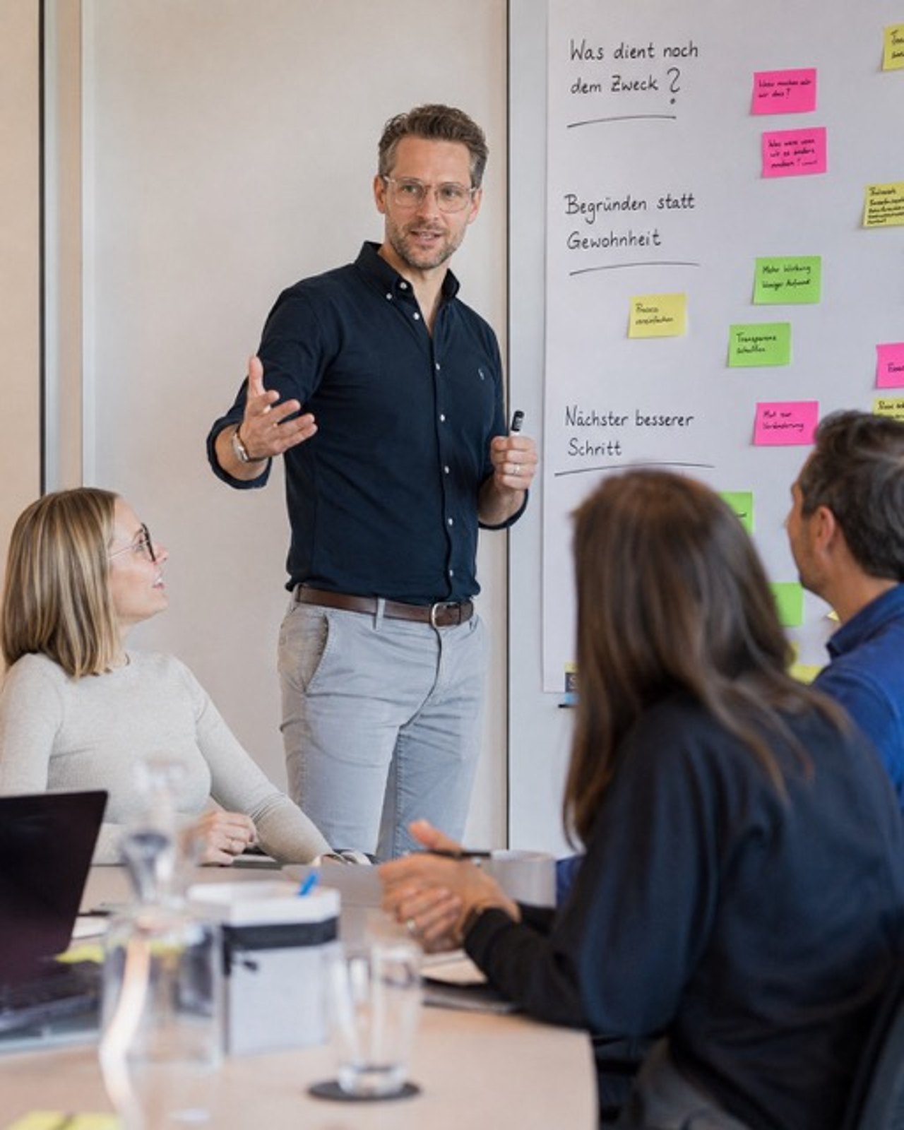 Trainer spricht vor einer Wand mit Haftnotizen zu Teilnehmenden eines Inhouse-Seminars