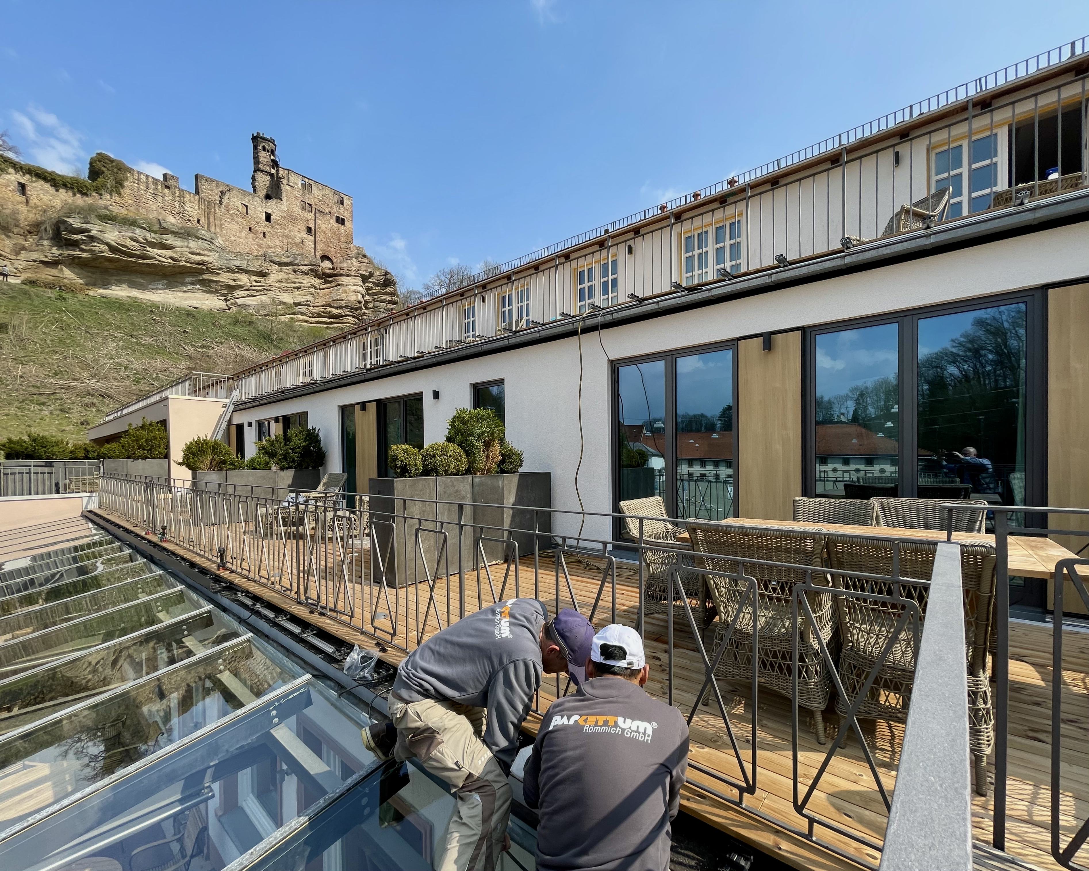 Handwerker von parkettum bei Arbeiten an einer Terrasse vor einem Gebäude