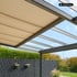 Pergola mit beigem Sonnenschutz, Glasdach, schwarzem Sichtschutz und Hecke.