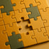 Gelbe und graue Puzzleteile, ein fehlendes Teil in der Mitte.