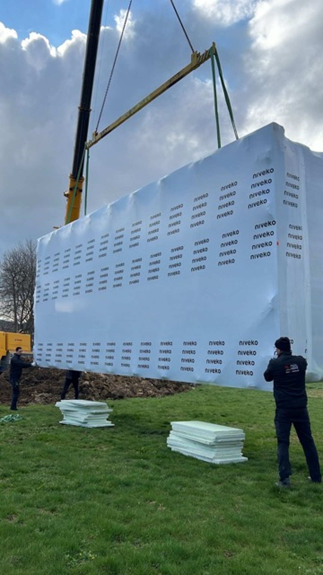 Kran hebt ein verpacktes Fertigbecken über das Haus in den Garten