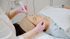 Eine Frau erhält eine Mikrodermabrasion-Gesichtsbehandlung von einem Kosmetiker in pinken Handschuhen.