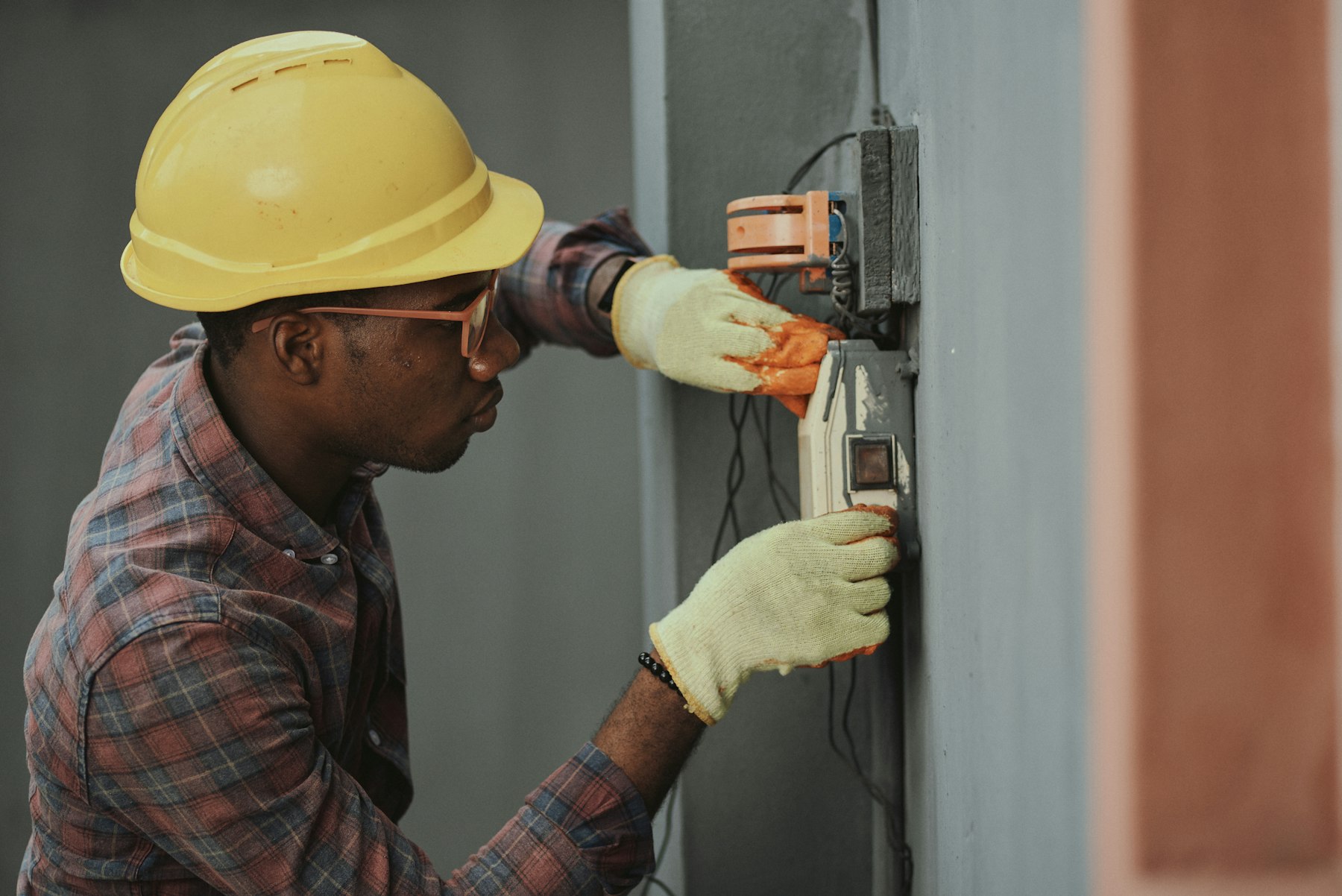 Licensed electrician in a hard hat installing wiring for an EV charger circuit