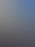Ein Fensterputzer seilt sich an einer modernen Gebäudefassade mit vielen Fenstern unter blauem Himmel ab.