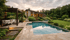 Haus mit Pool, Terrasse und Garten bei Sonnenuntergang.