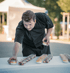 Koch in schwarzer Uniform arrangiert Dessertgläser auf einem weißen Tisch im Freien.