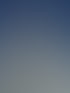 Hohes weißes Gebäude mit grauen Akzenten und Gerüsten vor blauem Himmel.