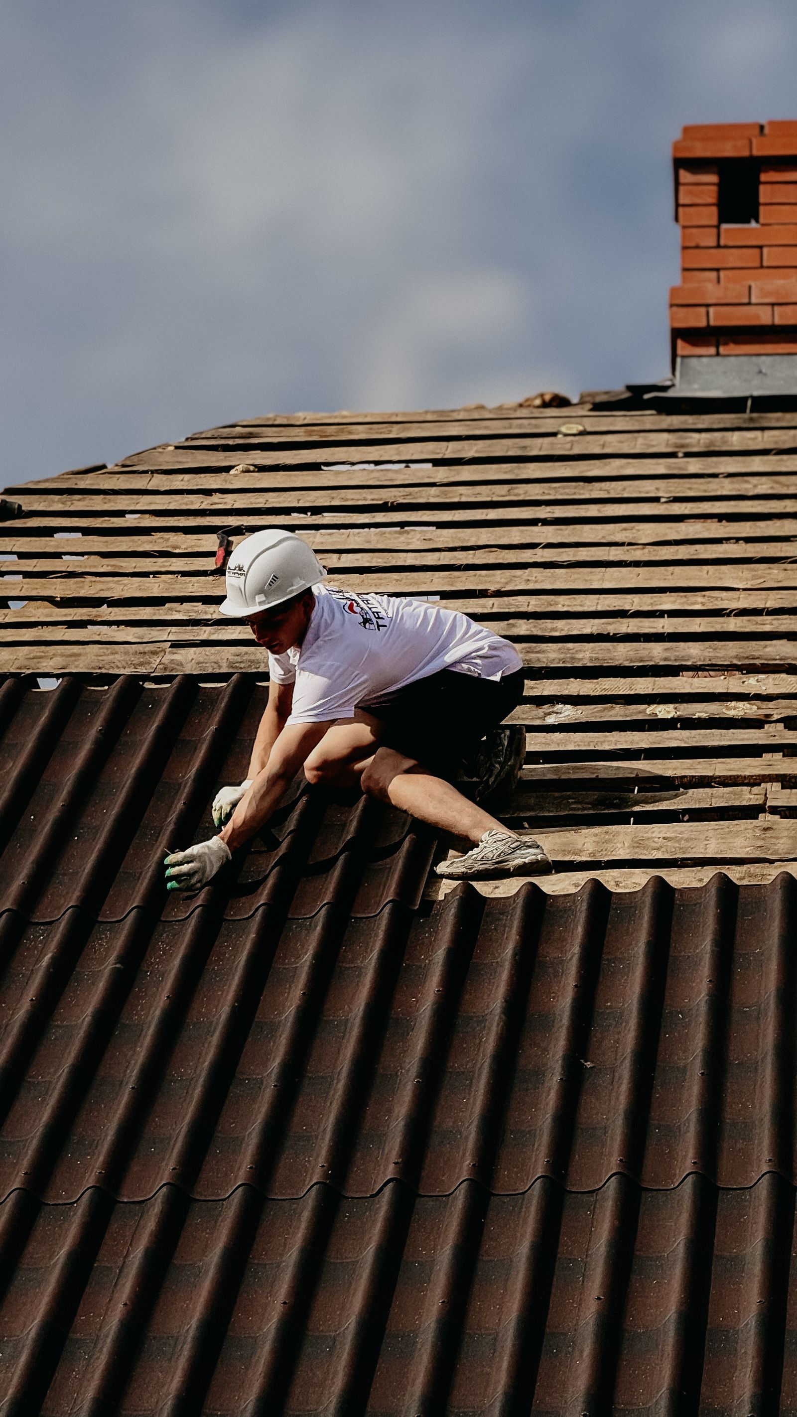 Roofer in safety gear working along a sloped roof surface