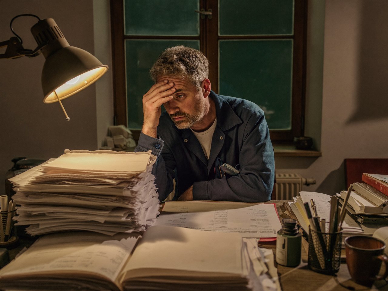 Handwerksmeister sitzt abends über Papierkram im Büro