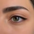Nahaufnahme eines grünen Auges mit schwarzem Eyeliner und einer gepflegten Augenbraue.