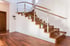 Moderne Holztreppe mit Edelstahlgeländer, die zu einer oberen Etage führt.