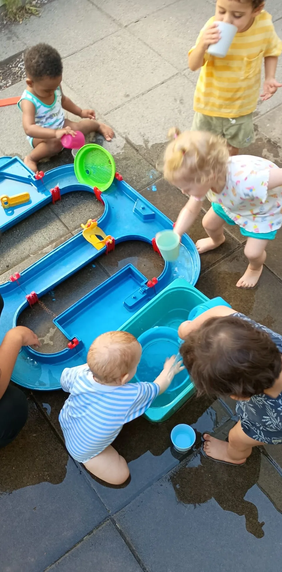 Kinder spielen an der Wasserbahn auf der Terrasse der Kita.