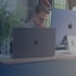 Mann mit Brille arbeitet an einem MacBook-Laptop und iMac-Monitor.