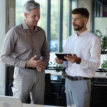 Titelbild zum kostenlosen Skript „Pitch-Formeln für Tech-Experten“: zwei Männer besprechen Notizen am Tablet
