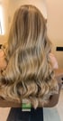Rückansicht von langem, gewelltem Haar mit blonden Balayage-Highlights in einem Friseursalon.