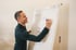 Mann in dunkelgrünem Hemd schreibt auf Flipchart mit blauem Marker.