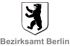 Wappen von Berlin mit schwarzem Bären auf weißem Schild, darunter der Text "Bezirksamt Berlin".