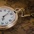 Goldene Taschenuhr mit Kette auf einer Weltkarte.