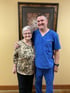 A doctor in blue scrubs with an elderly woman.