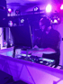 DJ Weihrauch live bei Event mit violettem Licht und professionellem DJ-Equipment