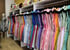 Bunte Dirndl und Trachtenkleider hängen nach Farben sortiert auf Kleiderbügeln in einem hellen Ladengeschäft.