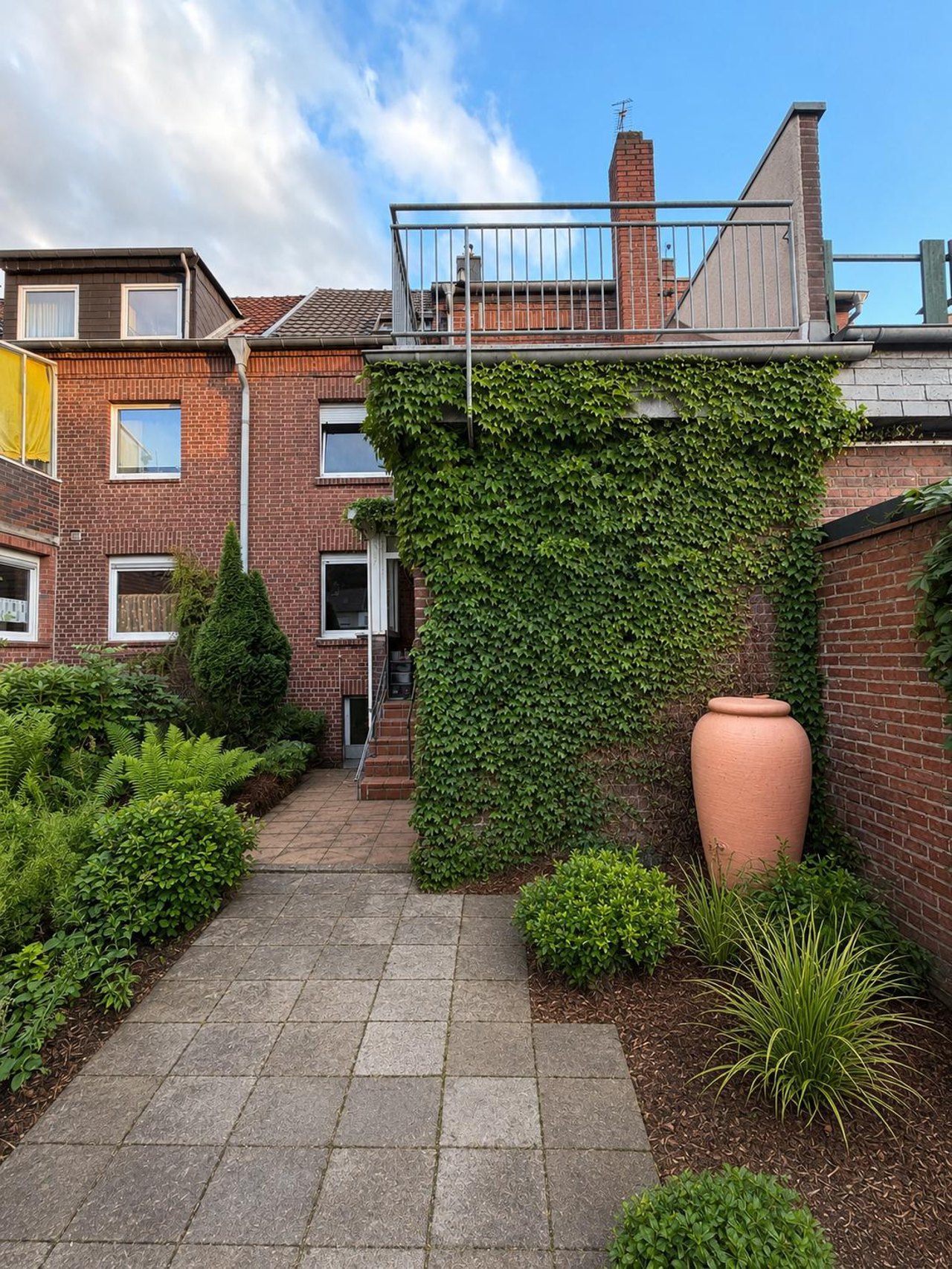 Das Haus von der Gartenseite mit gepflastertem Weg