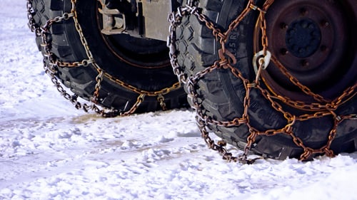 Tires fitted with snow chains on a snow-covered mountain road, the equipment chain controls require of Corona, California drivers heading up to the snow.
