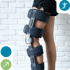 Person's leg with a black knee brace against a white brick wall.