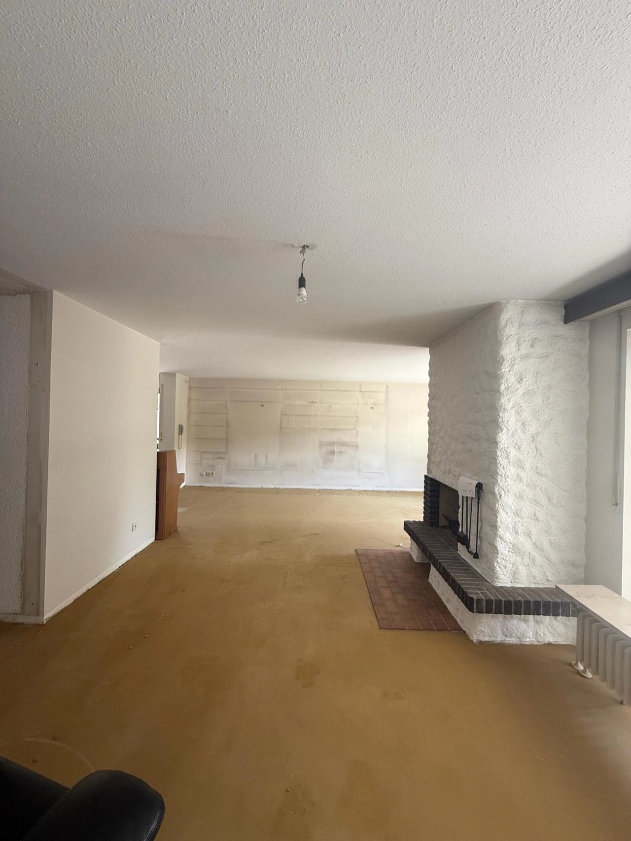 Großes entkerntes Wohnzimmer mit Kamin nach einer Nachlassauflösung in Füssen