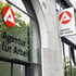 Agentur für Arbeit Logo und Schriftzug auf einem Gebäude; ein Schild hängt an der Wand, ein weiterer Schriftzug auf dem Fenster.
