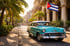 Türkisfarbenes Oldtimer-Auto parkt vor einem Gebäude mit Kuba-Flagge und Palmen in Havanna.